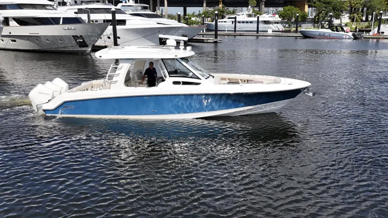 Slide: The Image of 2020 Boston Whaler 350 Realm boat cruising in a marina with yachts in the background. - 1