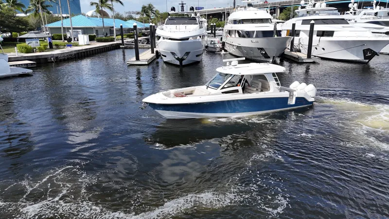 Slide: The Image of 2020 Boston Whaler 350 Realm cruising in a marina with yachts and palm trees. - 10