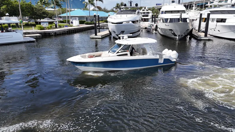 Slide: The Image of 2020 Boston Whaler 350 Realm boat cruising in a marina with yachts docked nearby. - 11