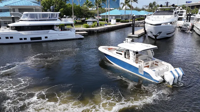 Slide: The Image of 2020 Boston Whaler 350 Realm cruising in a marina with luxury yachts. - 13