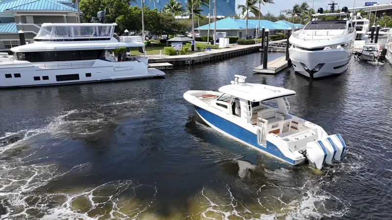 Slide: The Image of 2020 Boston Whaler 350 Realm cruising in marina with luxury yachts. - 14