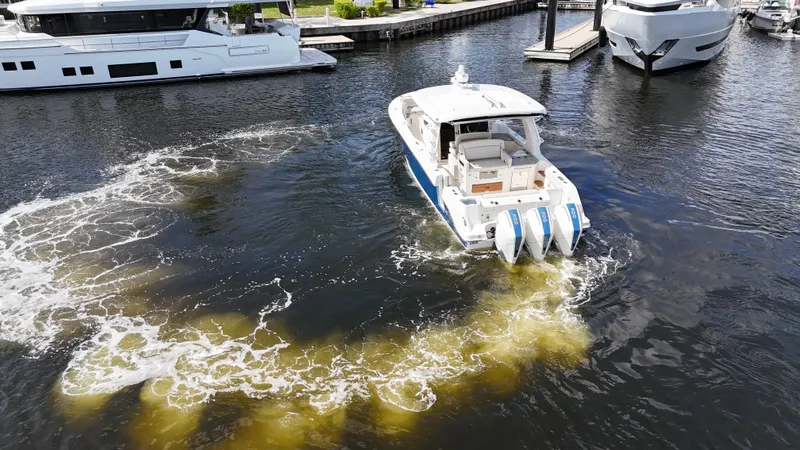 Slide: The Image of 2020 Boston Whaler 350 Realm boat navigating marina waters with visible wake. - 15