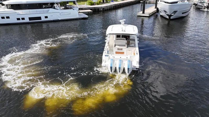 Slide: The Image of 2020 Boston Whaler 350 Realm boat maneuvering in marina with visible wake. - 16