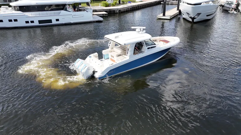 Slide: The Image of 2020 Boston Whaler 350 Realm cruising in marina, surrounded by yachts. - 18