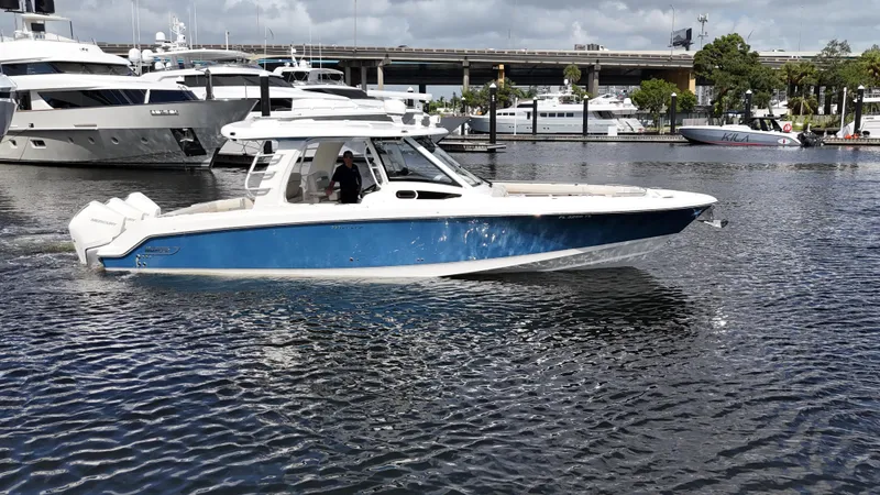 Slide: The Image of 2020 Boston Whaler 350 Realm boat cruising in a marina with yachts in the background. - 2