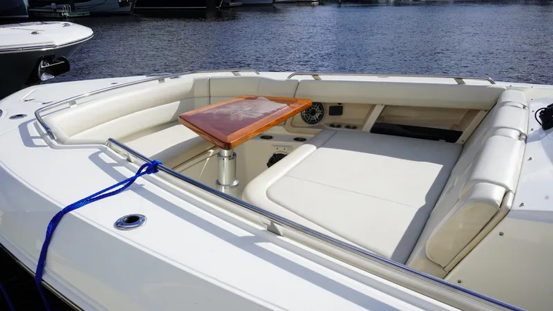 Slide: The Image of 2020 Boston Whaler 350 Realm boat interior with seating and table, docked by the water. - 22