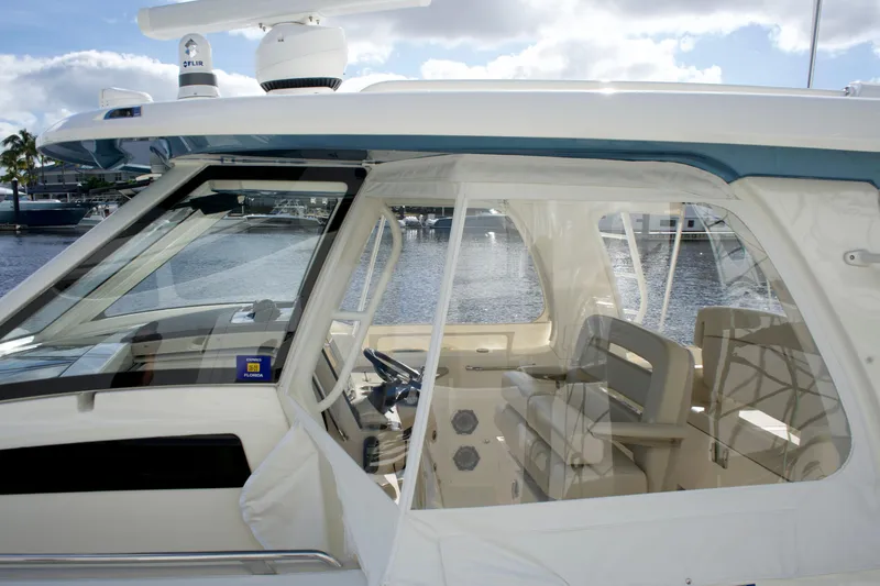 Slide: The Image of 2020 Boston Whaler 350 Realm boat interior with helm and seating, docked by the water. - 25