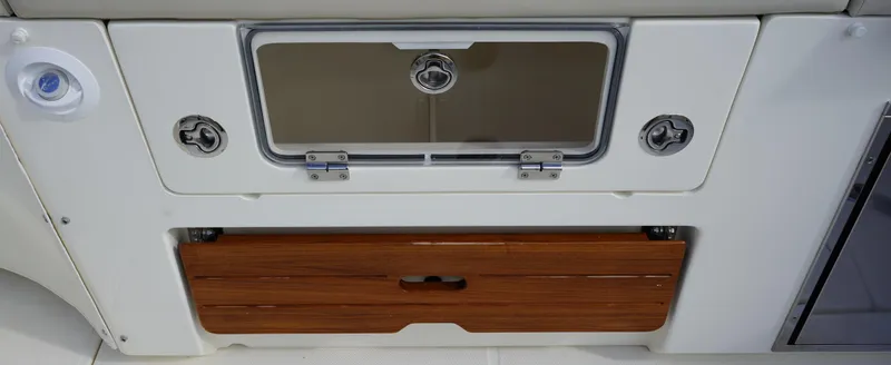 Slide: The Image of 2020 Boston Whaler 350 Realm storage compartment with wood finish and secure latches. - 31