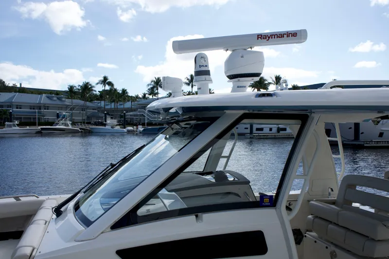 Slide: The Image of 2020 Boston Whaler 350 Realm boat docked, featuring Raymarine equipment, with a scenic marina backdrop. - 45