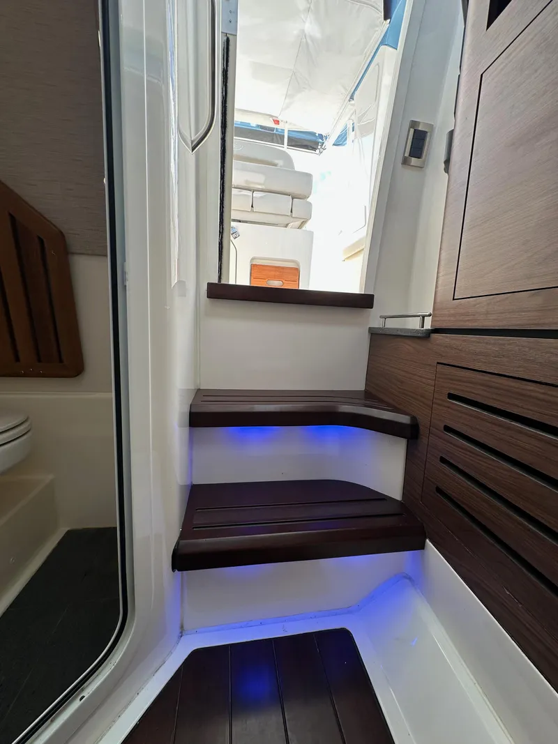 Slide: The Image of Interior stairs of 2020 Boston Whaler 350 Realm with blue LED lighting. - 54
