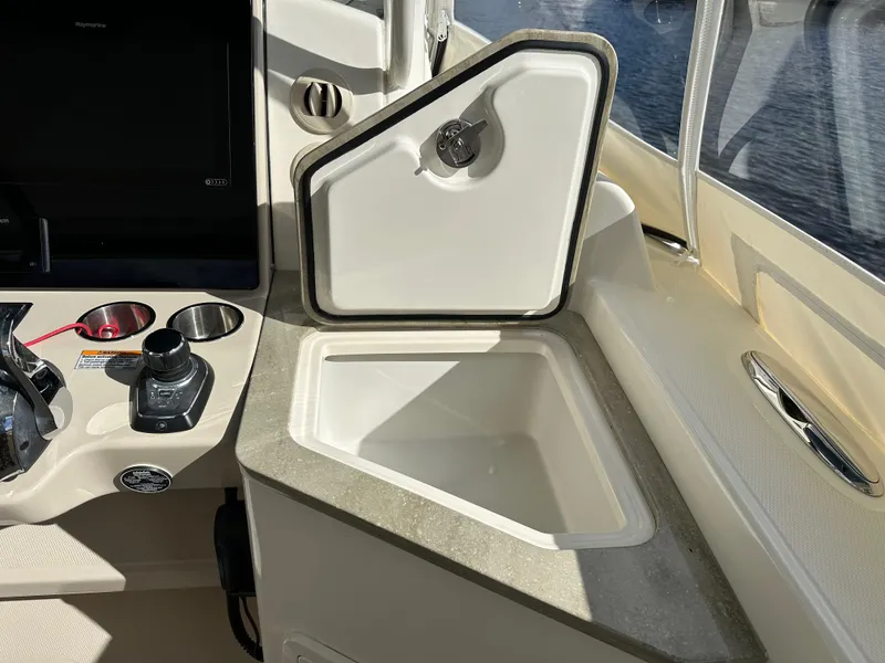 Slide: The Image of 2020 Boston Whaler 350 Realm boat interior with open storage compartment and control panel. - 56