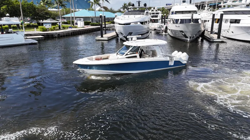 Slide: The Image of 2020 Boston Whaler 350 Realm cruising in a marina with yachts in the background. - 9