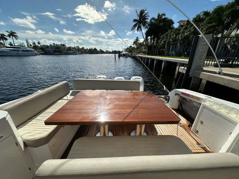 Slide: The Image of 2018 Azimut Verve 40 yacht deck with wooden table, docked by a scenic waterfront. - 26
