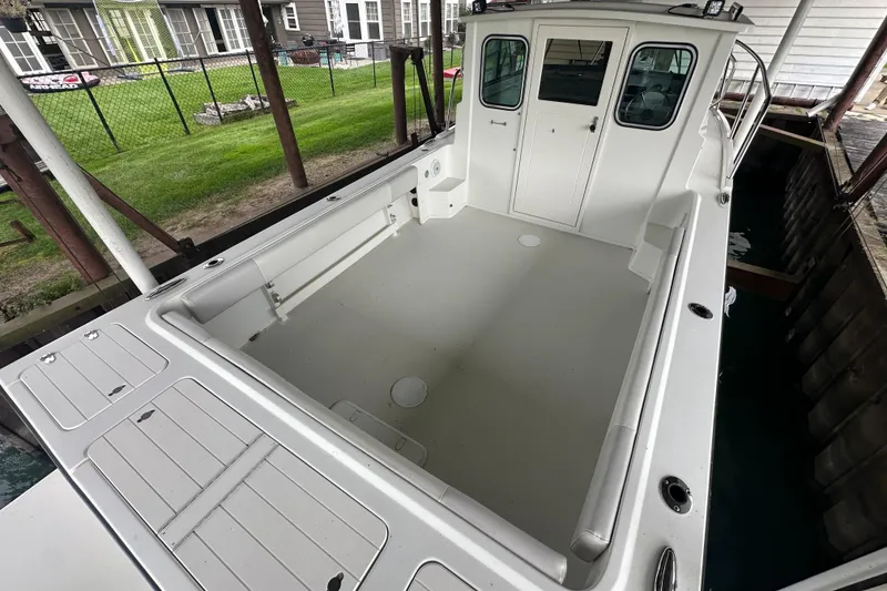 Slide: The Image of 2016 Parker 2320 SL Sport Cabin boat docked, spacious deck, white exterior. - 14