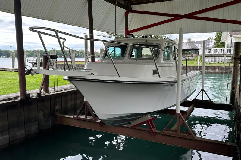 Slide: The Image of 2016 Parker 2320 SL Sport Cabin boat on lift in covered dock. - 2
