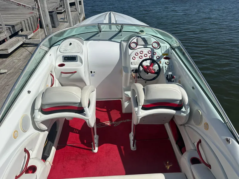 Slide: The Image of Interior of a 2000 Baja 342 boat with white and red seating, docked by water. - 18