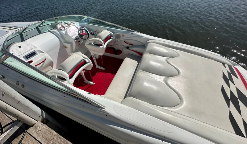 Slide: The Image of Interior of a 2000 Baja 342 boat with white and red seating, docked by water. - 20