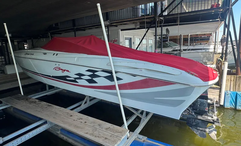 Slide: The Image of 2000 Baja 342 speedboat with red cover, docked in a marina. - 22