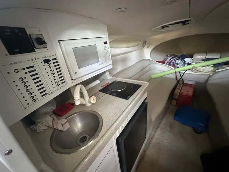 Slide: The Image of Interior of a 2000 Baja 342 boat featuring a kitchenette with microwave and sink. - 29