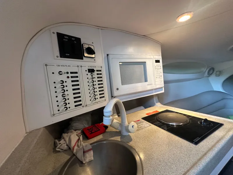 Slide: The Image of Compact boat kitchen with microwave, sink, and stove in a 2000 Baja 342 model. - 32