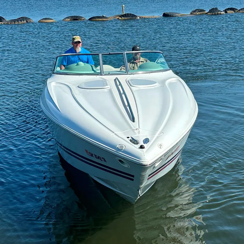 Slide: The Image of 2000 Baja 342 boat on water with two people onboard, near rocky shoreline. - 4