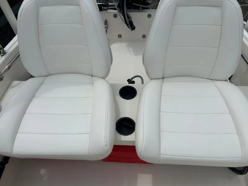 Slide: The Image of 2018 Boston Whaler 130 Super Sport boat interior with white cushioned seats and cup holders. - 10
