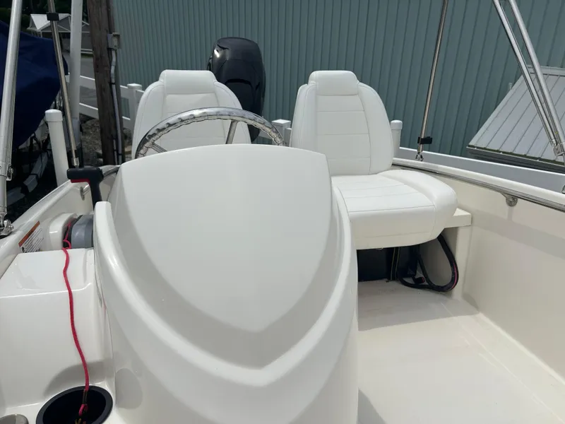 Slide: The Image of 2018 Boston Whaler 130 Super Sport interior with white seating and steering wheel. - 11