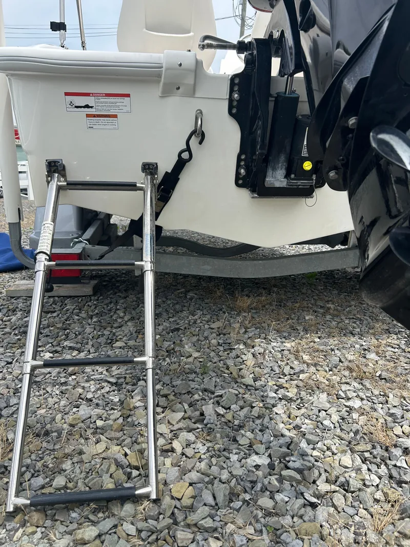Slide: The Image of 2018 Boston Whaler 130 Super Sport boat with ladder on gravel surface. - 17