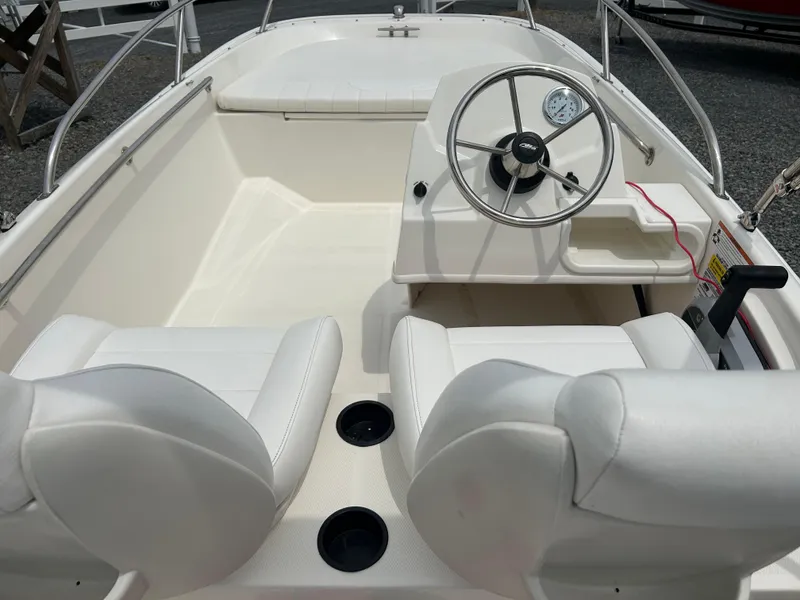 Slide: The Image of 2018 Boston Whaler 130 Super Sport boat interior with steering wheel and white seating. - 18