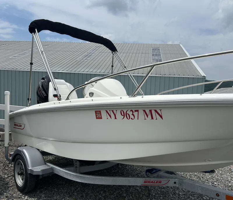 Slide: The Image of 2018 Boston Whaler 130 Super Sport boat on trailer, parked outdoors. - 2