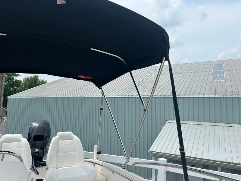 Slide: The Image of 2018 Boston Whaler 130 Super Sport with canopy, parked near metal-roofed buildings. - 5
