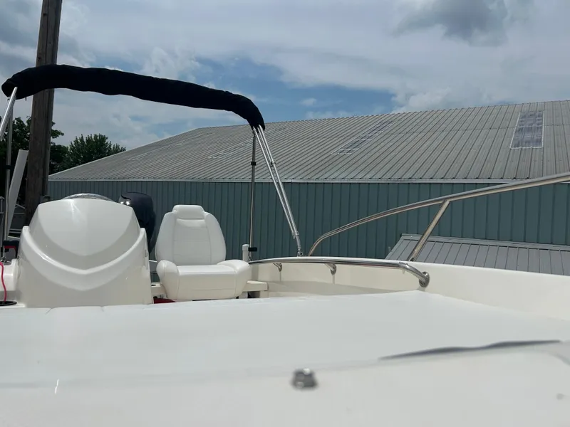 Slide: The Image of 2018 Boston Whaler 130 Super Sport boat with white seating and canopy, under cloudy sky. - 6