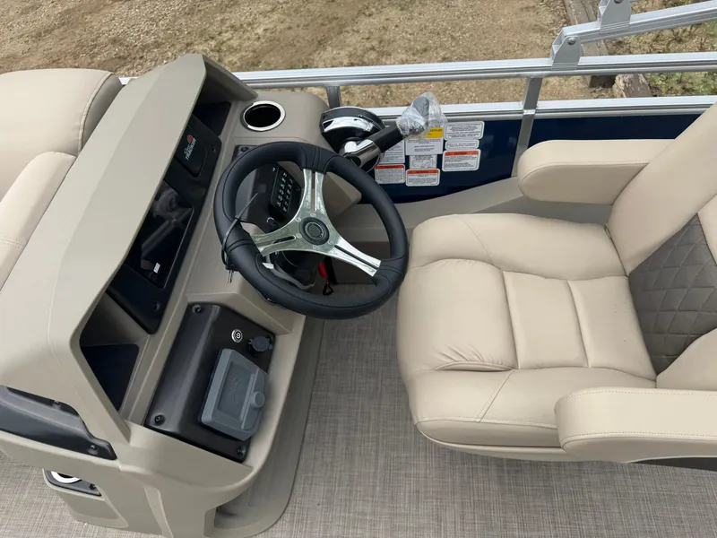 Slide: The Image of 2025 Sun Tracker Fishin' Barge 22 XP3 helm with beige seating and steering wheel. - 11