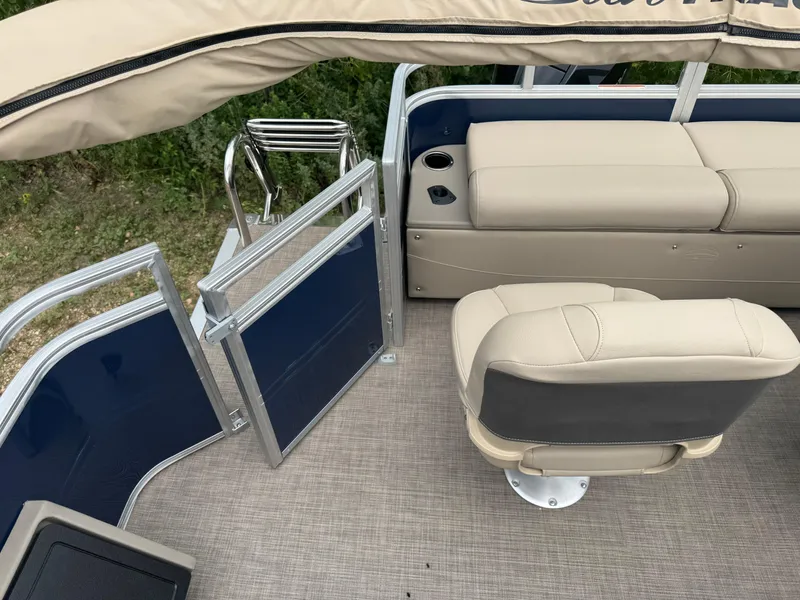 Slide: The Image of 2025 Sun Tracker Fishin' Barge 22 XP3 interior with beige seating and blue paneling. - 14