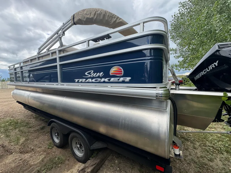 Slide: The Image of 2025 Sun Tracker Fishin' Barge 22 XP3 pontoon boat with Mercury engine, parked on trailer. - 5