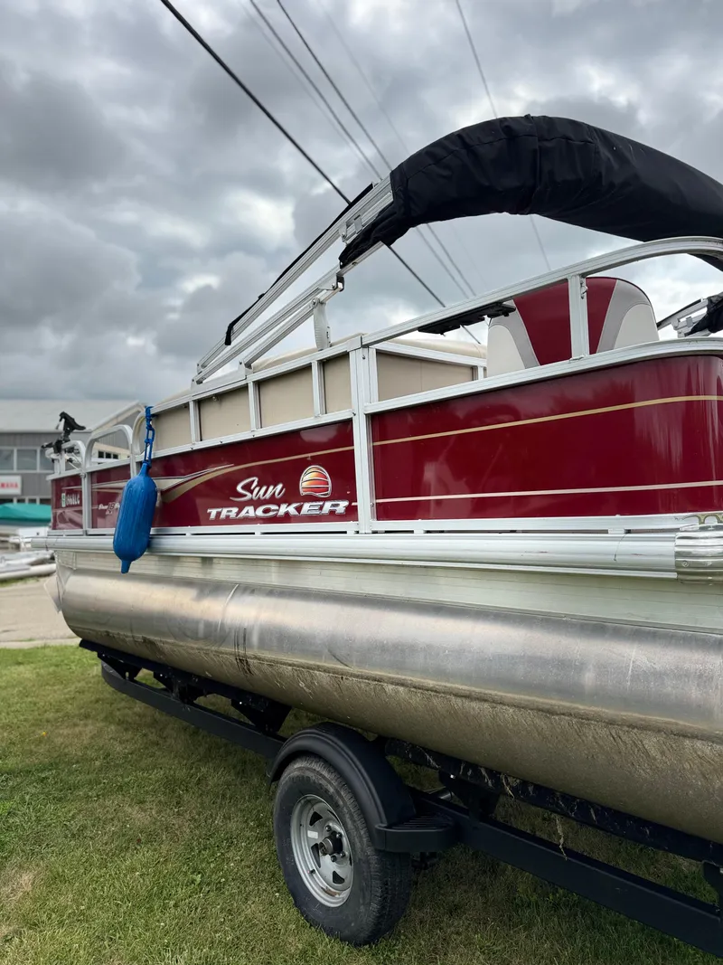 Slide: The Image of 2022 Sun Tracker Bass Buggy 18 DLX pontoon boat on trailer, cloudy sky background. - 7