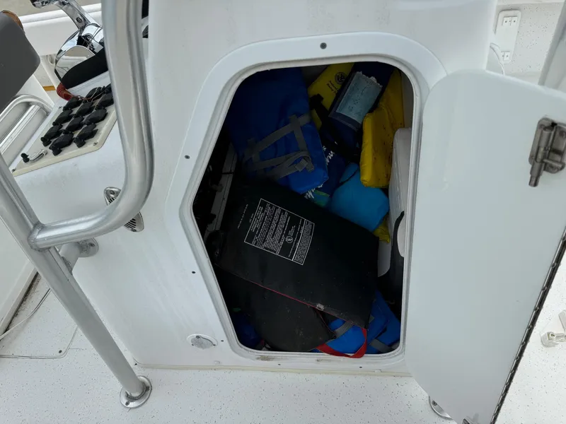 Slide: The Image of Open storage compartment on 2011 Carolina Skiff 25 Elite SS boat, containing various items. - 10