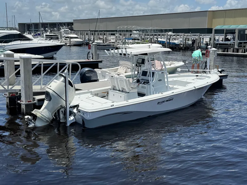 Slide: The Image of 2019 Blue Wave 2800 Pure Hybrid boat docked at marina, clear sky background. - 1