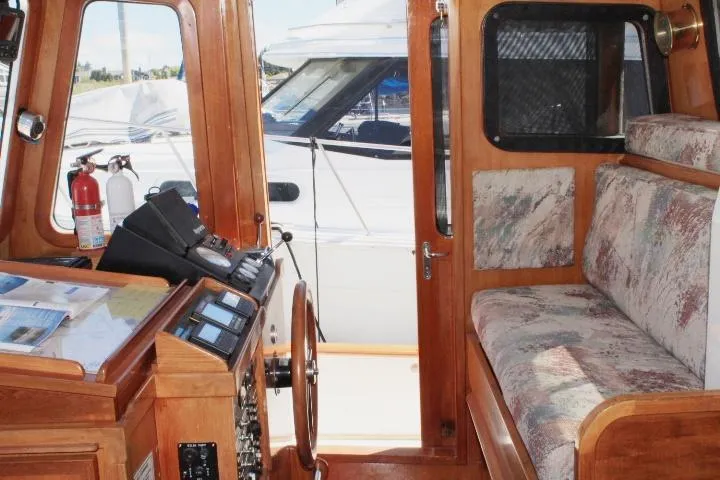 Slide: The Image of 1989 Eagle Pilothouse interior with wooden helm, control panels, and cushioned seating. - 26