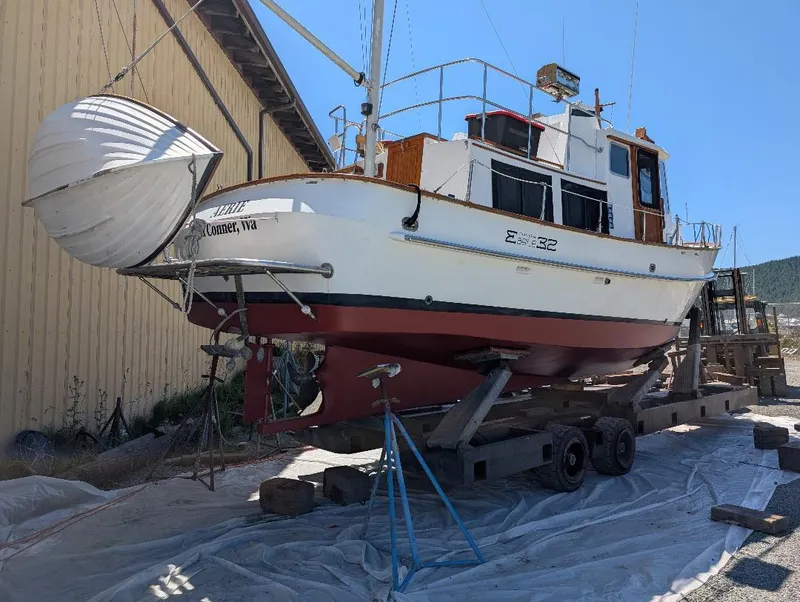 Slide: The Image of 1989 Eagle Pilothouse boat on trailer, docked near a wooden building under clear blue sky. - 4