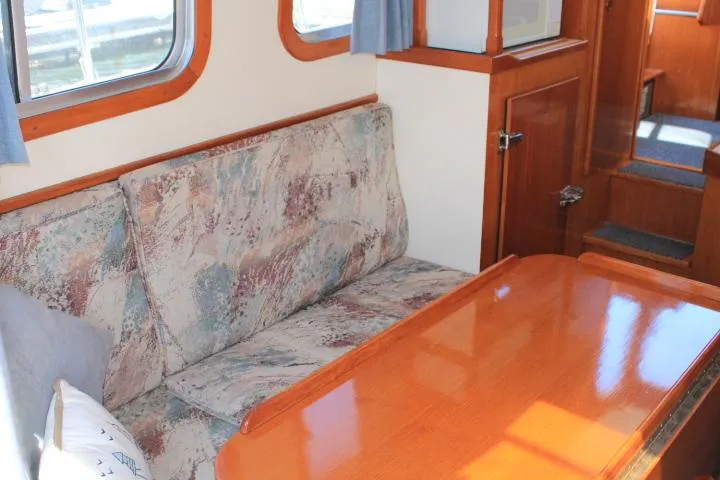 Slide: The Image of 1989 Eagle Pilothouse interior with wooden table, patterned sofa, and windows. - 56
