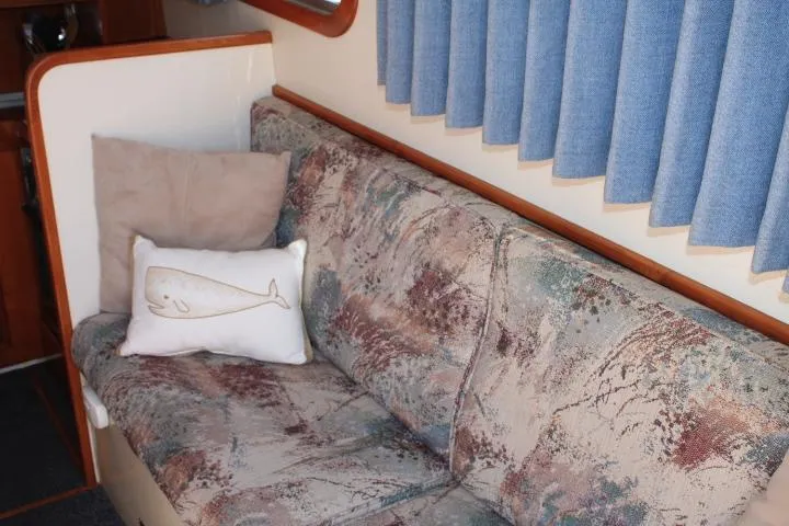 Slide: The Image of 1989 Eagle Pilothouse interior with patterned sofa, whale pillow, and blue curtains. - 58