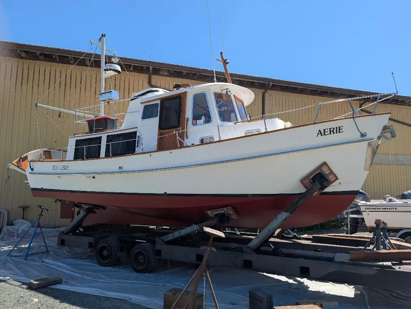 Slide: The Image of 1989 Eagle Pilothouse boat named "Aerie" on trailer, docked near a yellow building. - 3