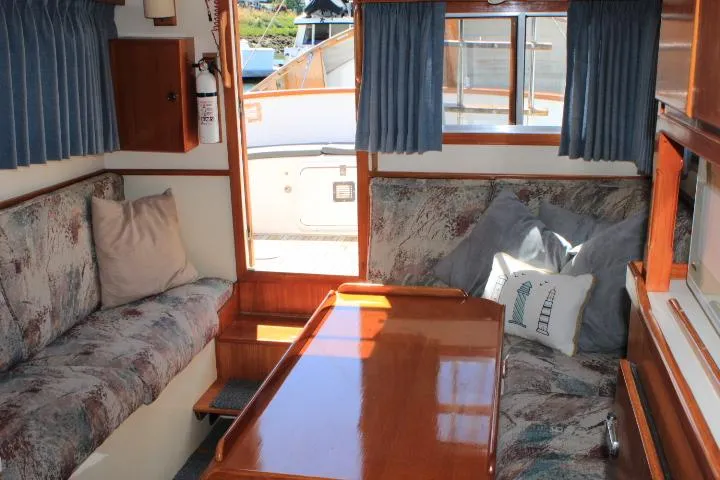 Slide: The Image of Cozy interior of a 1989 Eagle Pilothouse boat with cushioned seating and wooden table. - 54
