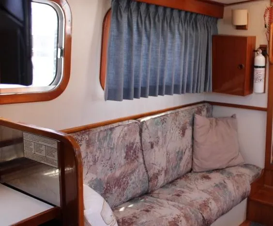 Slide: The Image of 1989 Eagle Pilothouse interior with patterned sofa, blue curtains, and wooden accents. - 57