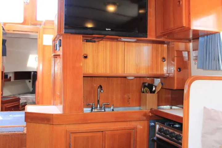 Slide: The Image of 1989 Eagle Pilothouse interior with wooden cabinetry, sink, and mounted TV. - 59