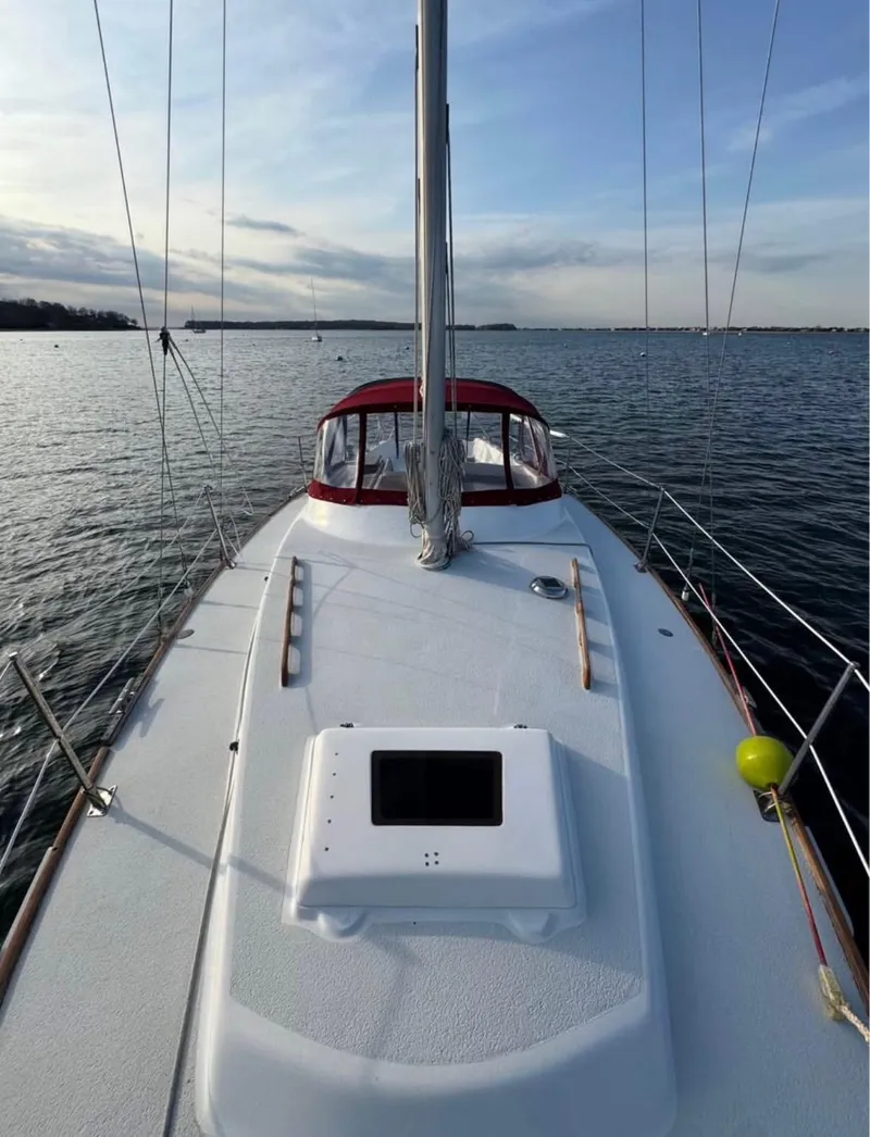 Slide: The Image of 1979 Morgan Out Island sailboat on calm water, featuring a spacious deck and red canopy. - 4