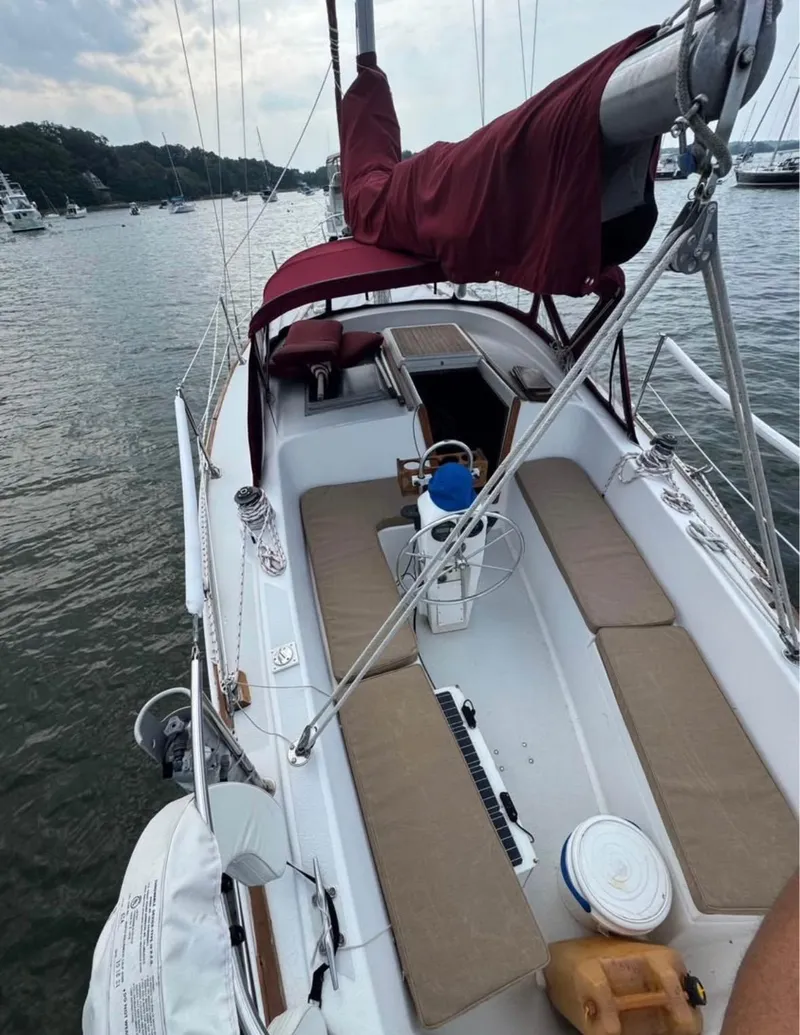 Slide: The Image of 1979 Morgan Out Island sailboat with maroon sail cover, docked in a serene harbor. - 5