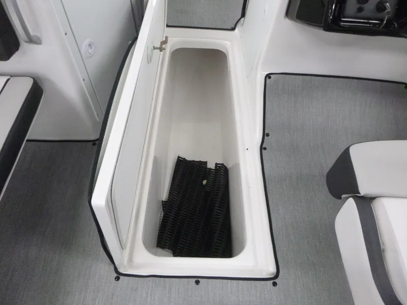 Slide: The Image of 2025 Yamaha Boats AR195 storage compartment with open lid and interior mat. - 13