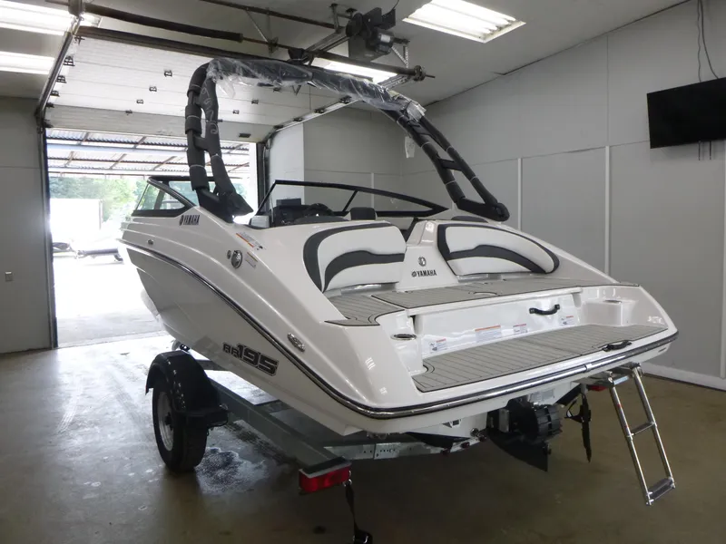 Slide: The Image of 2025 Yamaha Boats AR195 in showroom, rear view with swim platform and ladder. - 3
